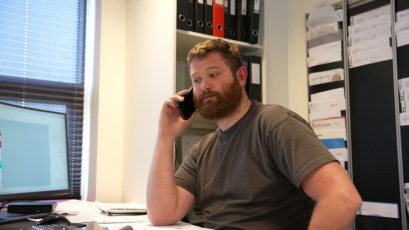 Medarbejder hos Carton Byg i telefonen på kontoret